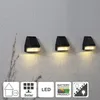 Three black solar-powered wall lights mounted on a textured gray wall, with icons indicating features at the bottom. Produktbild-Vorschau