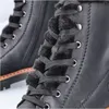 A close-up view of the lacing and fur lining of a black boot. Voir les images du produit