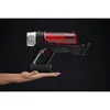 A hand holding a cordless vacuum cleaner against a black background. Produktbild-Vorschau