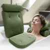 A woman relaxing in a bathtub with a green bath pillow. Produktbild-Vorschau