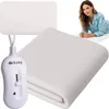 A woman in pajamas lies on a heated mattress pad, with a close-up of the pad and its controller in the foreground. Podgląd zdjęcia produktu