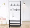 A black metal coat rack with three shelves for shoes, set against a white paneled wall. Produktbild-Vorschau