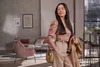 A woman stands in a modern living room, holding a jacket and a purse. Anteprima dell’immagine prodotto