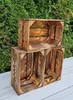 Two wooden crates are stacked on a light-colored surface, with a green hedge in the background. Produktbild-Vorschau