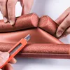 Hands are shown cutting a brown foam door seal with an orange utility knife. Náhled obrázku produktu