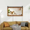 A mirror with a wooden frame is mounted on a wall above a sofa. The mirror reflects a living room scene with a cat sitting on a chair. Podgląd zdjęcia produktu
