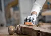 A person wearing gloves is sanding a wooden furniture piece. Produktbild-Vorschau