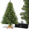 A green artificial Christmas tree with a wooden stand and a black storage bag. Produktbild-Vorschau