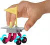 A hand is holding a small toy rover with a flag on top. Produktbild-Vorschau