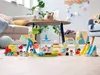 A collection of LEGO DUPLO amusement park toys arranged on a wooden floor in a living room setting. Podgląd zdjęcia produktu