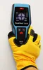 A hand wearing a yellow glove holds a digital wall scanner against a white wall. Anteprima dell’immagine prodotto