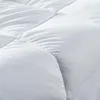 A close-up view of a white quilted comforter or mattress topper. Produktbild-Vorschau