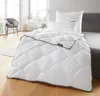 A neatly made bed with a white comforter and pillows in a bright bedroom. Produktbild-Vorschau