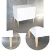 A white cabinet with wooden legs is shown against a textured gray wall and concrete floor. Close-up insets highlight the legs. Produktbild-Vorschau