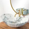 A close-up shot of a marble sink with a gold faucet, reflected in a mirror. Anteprima dell’immagine prodotto