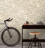 A bicycle is parked next to a desk with a rhino figurine and other decorative items, against a stone-patterned wall. Náhľad obrázku produktu
