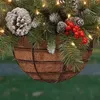 A close-up of a hanging Christmas decoration basket filled with pine needles, pinecones, and red berries. Anteprima dell’immagine prodotto