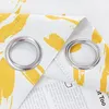 A close-up view of two grommets on a yellow and white patterned curtain, with text visible underneath. Produktbild-Vorschau