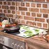 A kitchen counter with a stovetop, a cutting board with chopped vegetables, and a glass stovetop protector with a plant pattern. Náhľad obrázku produktu