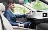 A man in a suit driving a car while wearing a Bluetooth headset. Produktbild-Vorschau