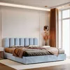 A bed with light blue upholstery and a tufted headboard is shown in a bedroom setting with warm lighting and natural light from a window. Anteprima dell’immagine prodotto