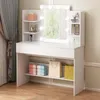 A white makeup vanity with a lighted mirror and shelves, displaying various cosmetic items and shopping bags. Náhled obrázku produktu