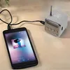 A small white cube speaker is connected to a smartphone playing music. Produktbild-Vorschau