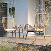 A rattan seating set for two on a wooden deck, with plants in the foreground and background. Náhled obrázku produktu