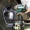 A hand wearing a glove is using a Makita cordless impact wrench to tighten lug nuts on a large tire. Produktbild-Vorschau