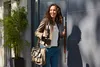 A woman is opening a door while holding a thermos. Produktbild-Vorschau