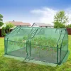 A small greenhouse with tomato plants inside, set up in a backyard with houses and trees in the background. Produktbild-Vorschau