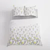 A duvet cover and two pillowcases with a daisy pattern are laid out on a bed. Produktbild-Vorschau