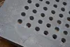 A close-up view of a cast iron grate with multiple circular holes. Anteprima dell’immagine prodotto