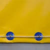 Close-up of two grommets on a yellow tarp, with a rope threaded through them. Produktbild-Vorschau