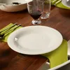 A white plate is set on a wooden table with a green napkin and cutlery. Náhľad obrázku produktu