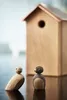 Two wooden bird figures in front of a wooden birdhouse. Náhled obrázku produktu