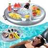 An inflatable pool tray filled with drinks and snacks floats in a swimming pool, with a woman relaxing on a float in the background. Náhled obrázku produktu