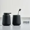 A black soap dispenser and a black toothbrush holder with a toothbrush are displayed on a light gray surface against a white background. Produktbild-Vorschau