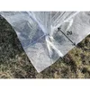 Close-up of a white mesh greenhouse cover on the ground. Voir les images du produit