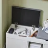 An open white storage bench with items inside, against a light green wall. Produktbild-Vorschau