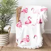 Weißes rundes Strandtuch mit rosa Flamingo-Druck und weißem Fransensaum, über einem Korbstuhl drapiert Anteprima dell’immagine prodotto