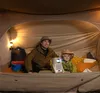 A father and son are watching a movie on a projector inside a tent. Produktbild-Vorschau
