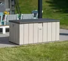 A storage box is placed on a patio next to a lawn, with outdoor furniture in the background. Podgląd zdjęcia produktu