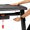 A person's hands are shown interacting with a treadmill, specifically plugging in a safety cord. Podgląd zdjęcia produktu