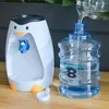A penguin-shaped water dispenser next to a large bottle of water that is being refilled. Produktbild-Vorschau