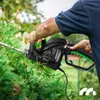 A person is using an electric hedge trimmer to trim a bush. Náhľad obrázku produktu