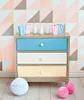 A dresser with colorful drawers and decorative items on top and around it, set against a geometric patterned wallpaper. Produktbild-Vorschau