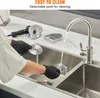 A person wearing black gloves is cleaning a blade of a shawarma knife under a faucet in a kitchen sink. Náhled obrázku produktu