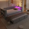 A modern bedroom with a grey upholstered daybed and a pull-out trundle bed, featuring built-in shelving and LED lighting. Produktbild-Vorschau