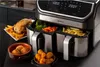 A dual-basket air fryer is shown with various foods cooked in it, including a whole chicken, french fries, vegetables, and fried snacks. Podgląd zdjęcia produktu